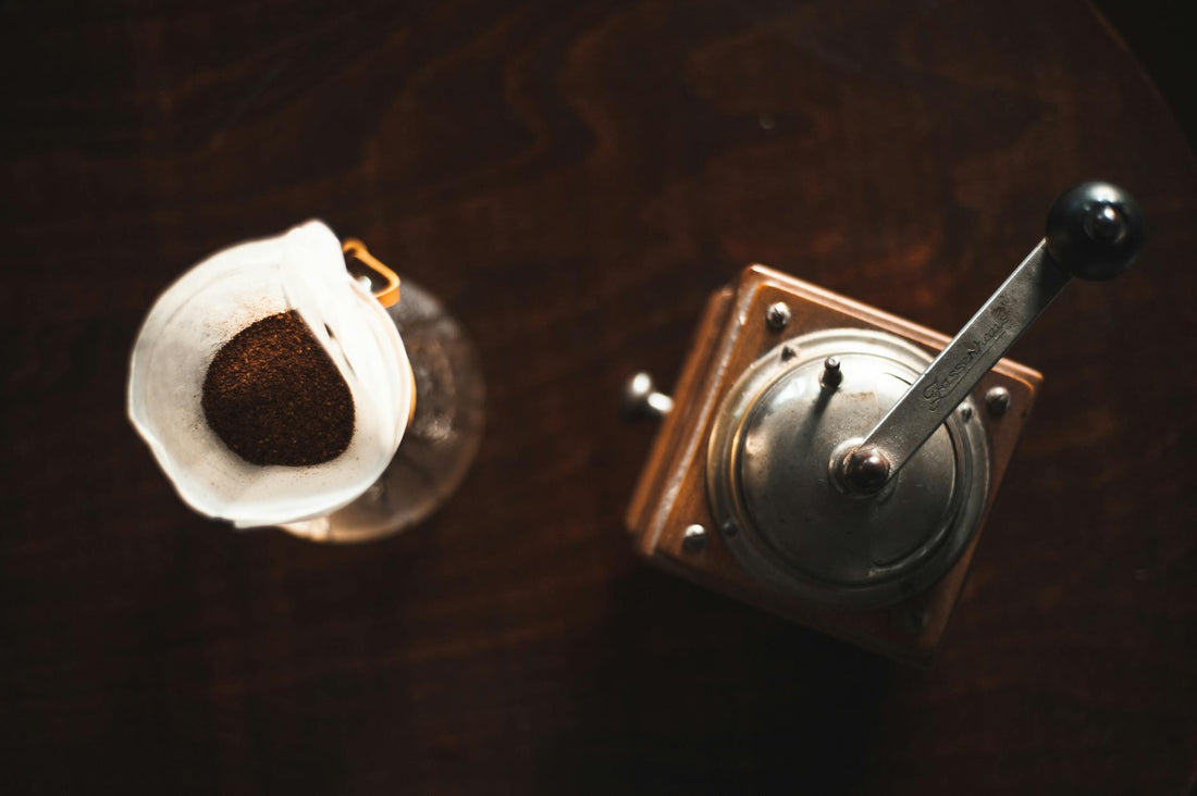 Coffee grinder and pour-over setup on wooden table, visual cue for grind size and brew method dial-in