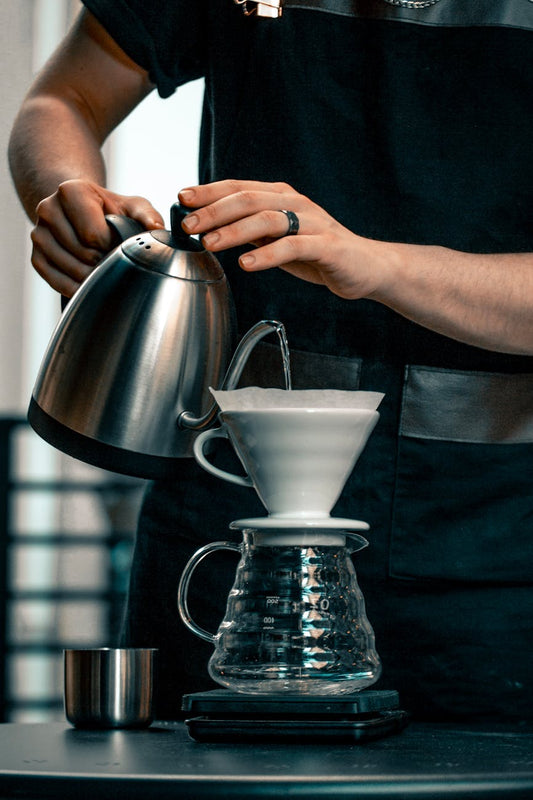 Pour-over kettle adding water to a coffee dripper, highlighting coffee water basics